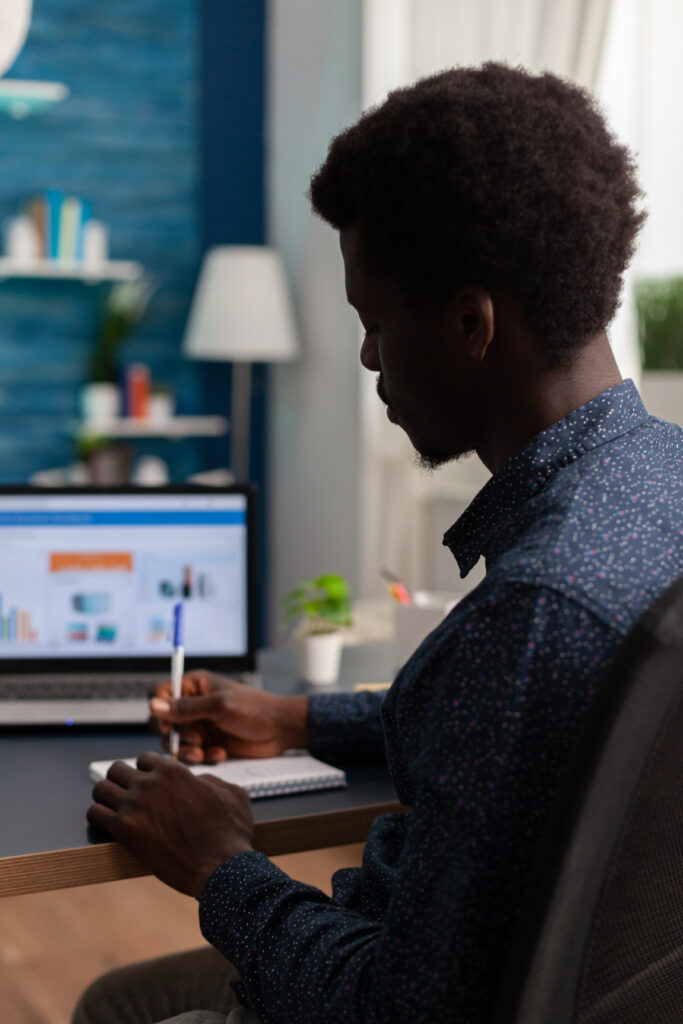 black student writing financial strategy on notebook