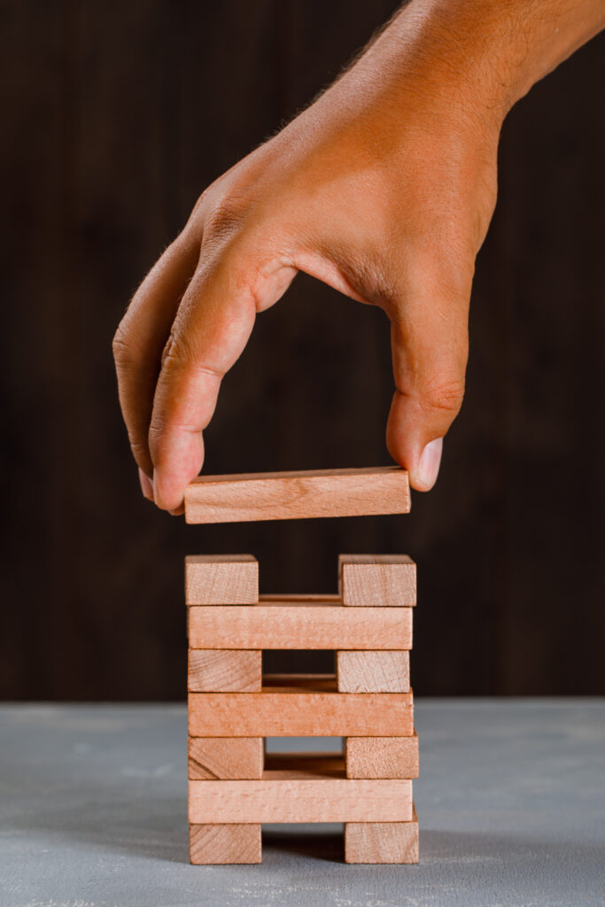 business project concept on wooden and plaster background side view. man building up tower.
